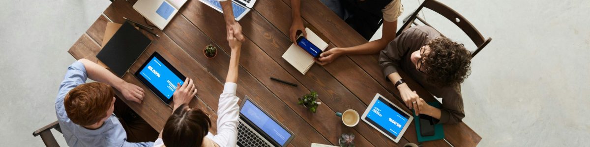 Top view of a diverse team collaborating in an office setting with laptops and tablets, promoting cooperation.